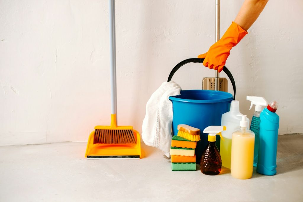 A selection of cleaning products like a brush, buckets, and sprays