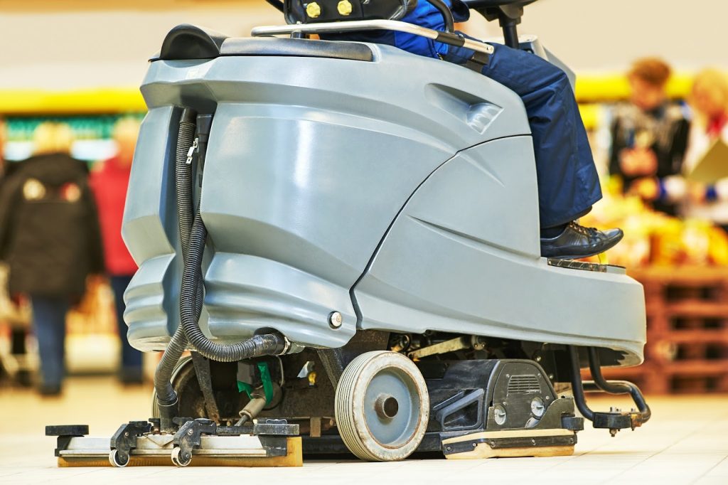 A close-up of a cleaner using a commercial floor scrubber for great results