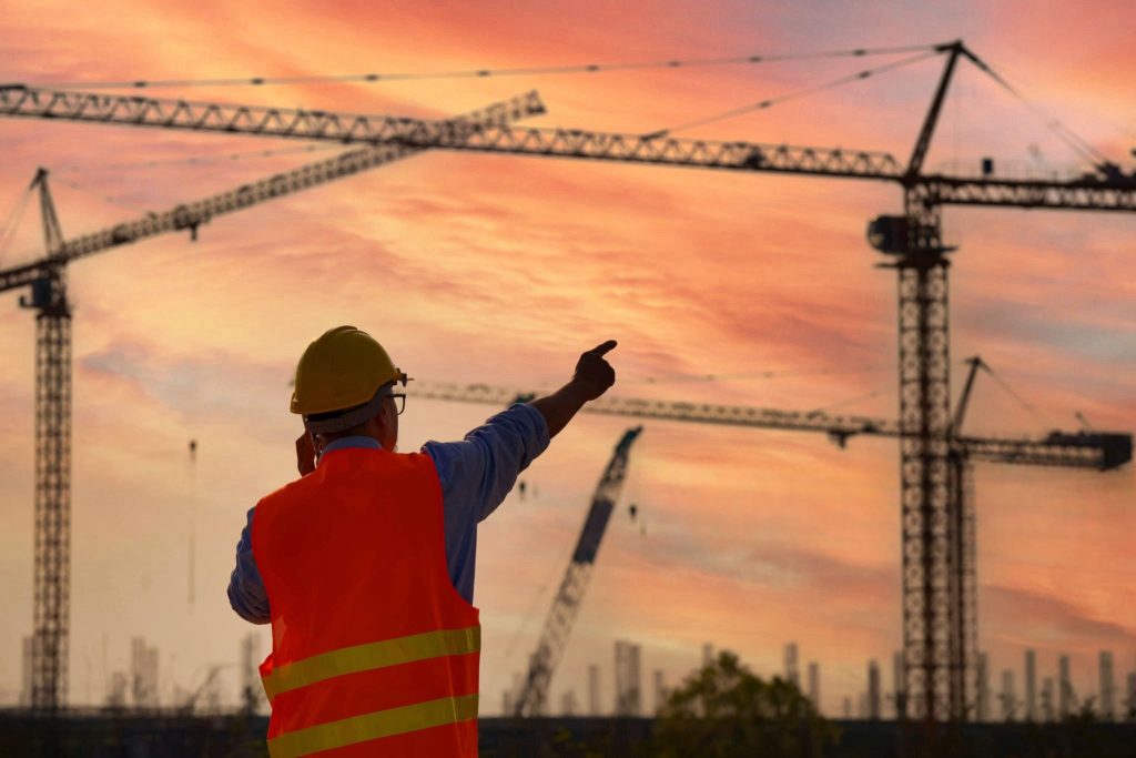 Silhouette of Asian Engineer or Investor and Worker working at Industrial Building  Real Estate project site.Team of Specialists Inspect Commercial, Project with large building. In the Background Crane Skyscraper."n