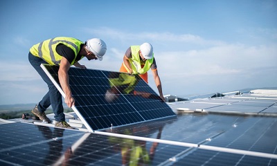 Team of two engineers installing solar panels on roof.