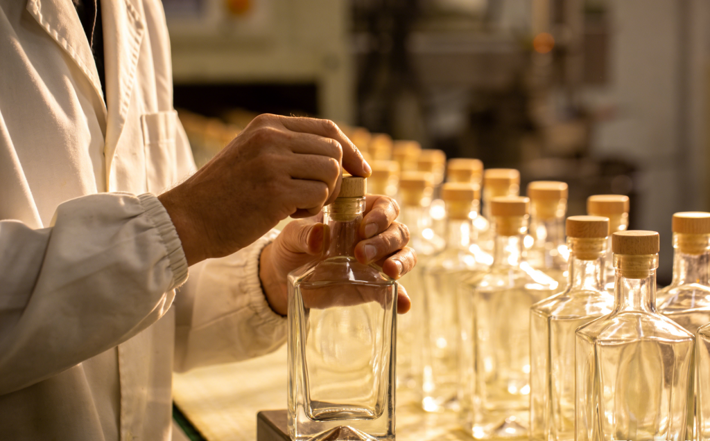 Мастер контроля качества на заводе Shandong Yuncheng Zhenghua проверяет посадку деревянной пробки в стеклянную бутылку, обеспечивая высокое качество продукции перед отправкой клиенту.