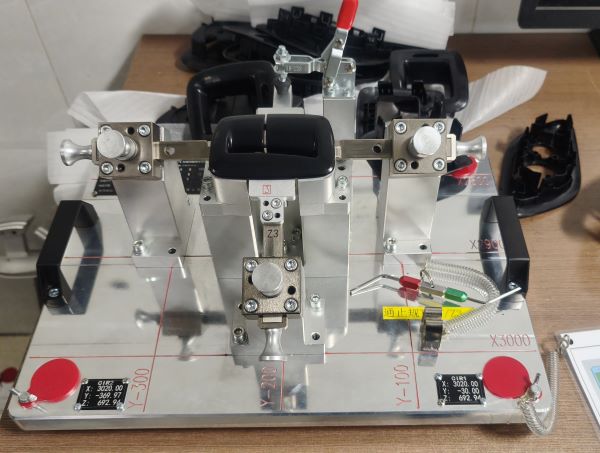 Решение от Xin Xiang: Полный цикл контроля от истока до верификации Когда проект зашел в тупик, нам представили компанию Xin Xiang Technology. Их технический подход, особенно их «Комплексное решение для продукта» (Complete Product Solution) для сложных пластиковых деталей, сразу же произвел впечатление. Сила Xin Xiang заключается в дальновидных технологических инвестициях и строгих процессах контроля качества: Предварительное моделирование течения расплава для прогнозирования рисков и точного контроля коробления: Xin Xiang интегрирует передовое программное обеспечение для CAE-анализа MoldEX3D на самой ранней стадии каждого проекта для проведения всестороннего анализа течения расплава в форме. Это выходит за рамки простого анализа заполнения и включает в себя полное моделирование процесса «Заполнение + Уплотнение + Коробление». Визуально прогнозируя поведение потока расплавленного пластика, неравномерную усадку при охлаждении и потенциальное коробление, которое может возникнуть, Xin Xiang может выявлять и решать потенциальные проблемы уже на этапе первоначального проектирования пресс-формы. Для нас это означало, что риски коробления изделия были сведены к минимуму еще до изготовления оснастки, что радикально сократило количество пробных отливок и сократило цикл разработки. Эта способность была продемонстрирована при разработке монтажного кронштейна, где Xin Xiang использовала анализ течения расплава для детального изучения времени заполнения, температуры фронта потока, линий сварки, давления заполнения, максимальной объемной усадки при уплотнении и общего смещения из-за коробления как для основной части, так и для защелок, гарантируя соответствие продукта всем спецификациям. Инновационная, нетрадиционная конструкция пресс-формы для преодоления сложной геометрии: Столкнувшись с проблемой глубоких ребер и нестандартных поднутрений в наших компонентах сиденья, техническая команда Xin Xiang продемонстрировала исключительную инновационность. Они не ограничиваются традиционными решениями, а создают продуманные, нетрадиционные конструкции пресс-форм на основе результатов CAE-моделирования и конкретных особенностей продукта. Например, в другом случае, связанном с верхней крышкой рулевой колонки автомобиля со сложными поднутрениями, затруднявшими извлечение, Xin Xiang успешно решила проблему, применив «механизм подъёмника с большим углом наклона». Такой подход, ориентированный на адаптацию конструкции под конкретную сложную геометрию, гарантирует, что пресс-форма точно воспроизводит дизайн изделия, предотвращает дефекты, вызванные ограничениями пресс-формы, и повышает вероятность успеха с первой пробной отливки. Контрольно-измерительная оснастка UCF для интерьера/экстерьера для обеспечения точности сборки: Контроль качества Xin Xiang распространяется не только на производственный процесс, но и на финальную стадию сборки. Они используют комбинированные контрольно-измерительные приборы UCF (Unit Check Fixture) для интерьера и экстерьера для проведения сборки и проверки продуктов. Эти профессиональные приборы имитируют реальные условия сборки, позволяя проводить строгий контроль размеров пластиковых деталей, геометрических допусков и точности подгонки. Это обеспечивает нам надежную гарантию качества, гарантируя, что каждая деталь, поставленная Xin Xiang, идеально сочетается с другими компонентами автомобиля, предотвращая доработки или простои на сборочной линии из-за несоответствия размеров. Xin Xiang явно включает «Проверку продукта» в свои услуги «под ключ», а в демонстрации оборудования упоминаются высокотехнологичные измерительные инструменты, такие как КИМ (координатно-измерительные машины), что дополнительно подтверждает ее возможности в области контроля качества.
